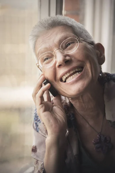 Старшая женщина дружелюбно разговаривает по мобильному телефону — стоковое фото