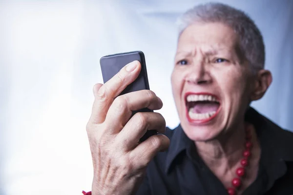 Oude dame schreeuwen tegen haar mobiele telefoon — Stockfoto