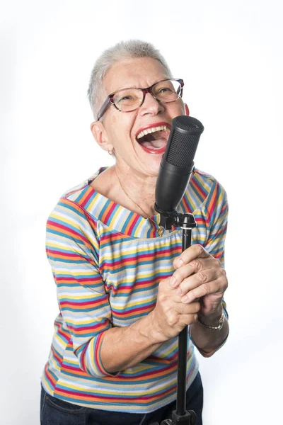 Mulher idosa sênior cantando em um microfone profissional — Fotografia de Stock