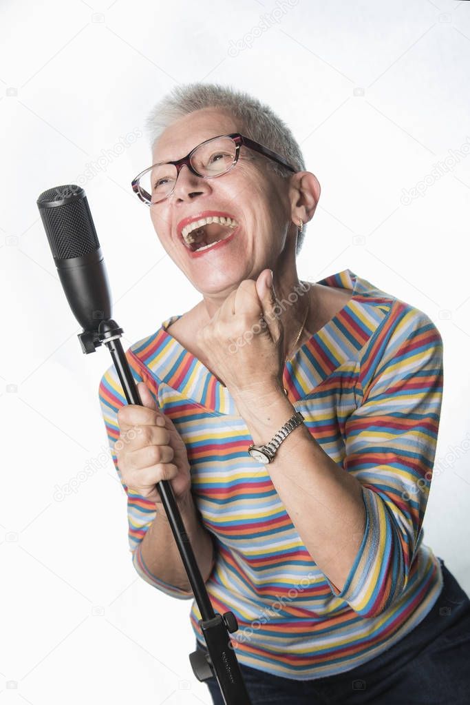 Senior old woman singing on a professional microphone