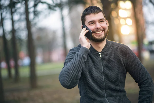 Jovem bonito falando em seu telefone em uma área urbana — Fotografia de Stock