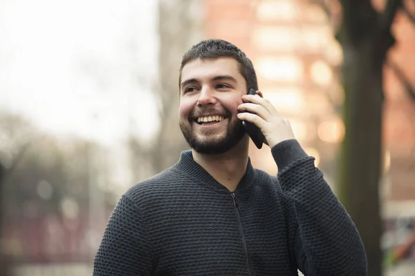 Jovem bonito falando em seu telefone em uma área urbana — Fotografia de Stock