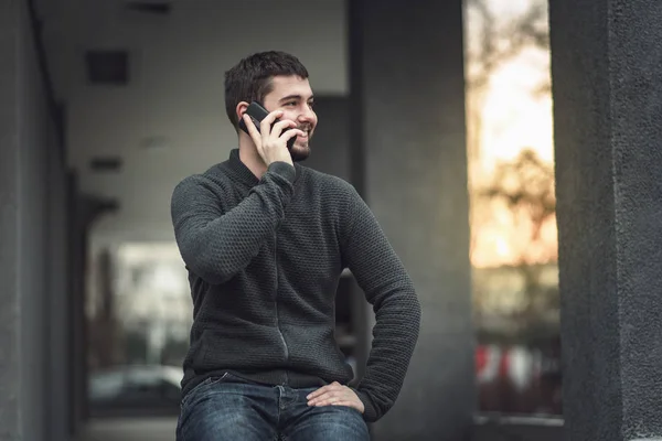 Pohledný mladý muž mluví o jeho telefonu v městské oblasti — Stock fotografie