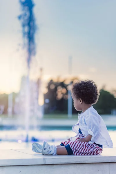 Cute baby girl playing next to fountain sprinklers — Stock Photo, Image