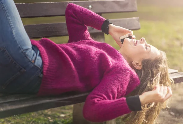 Freie fröhliche Frau, die ihr Handy an einem sonnigen Tag in einem Park benutzt — Stockfoto