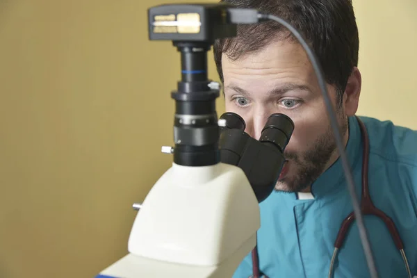 Młody lekarz badania pod mikroskopem — Zdjęcie stockowe
