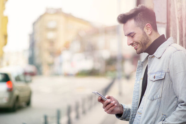 Young handsome man using his cell phone, enjoying a day on the street