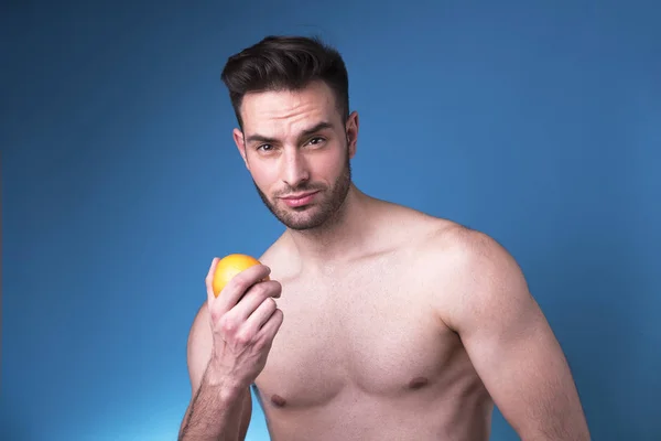 Attractive nude young man holding an orange — Stock Photo, Image