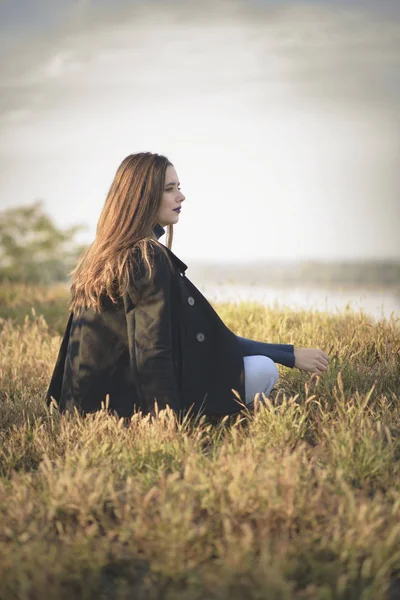 Sad woman sitting alone in an empty field