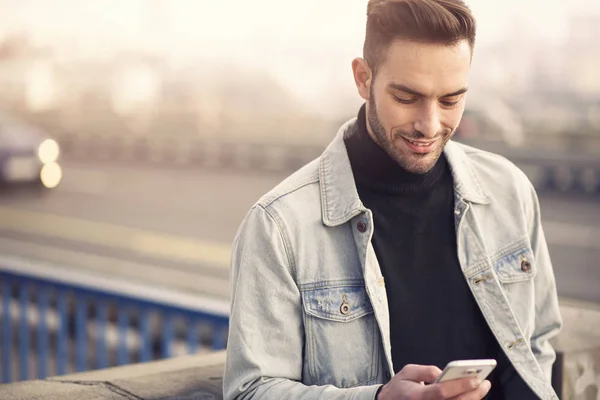 Junger gutaussehender Mann, der sein Handy benutzt und einen Tag auf der Straße genießt — Stockfoto