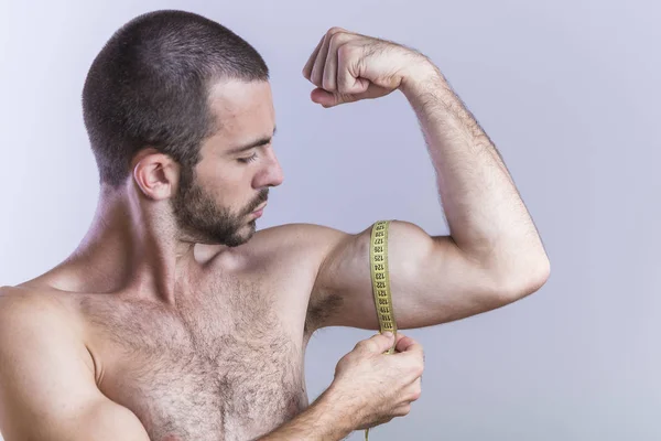 Athletic man measuring his biceps size — Stock Photo, Image