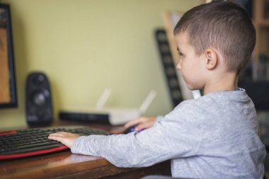 Genç çocuk bir masaüstü bilgisayarda oyun oynarken