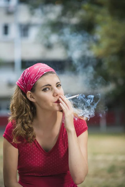 Red retro girl smoking in the park — Stock Photo, Image