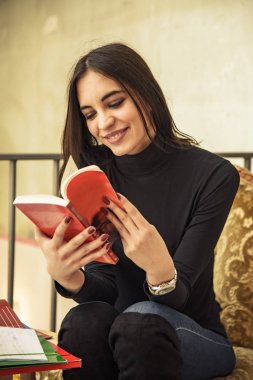 Genç kız öğrenci bir kafede bir kitap okuma
