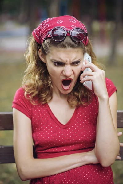 Arga pin up tjej skriker på sin smarta telefon — Stockfoto