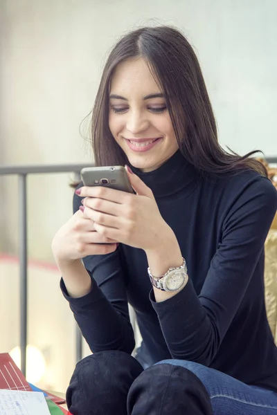 Jovem mulher desfrutando de uma xícara de café e falando em seu telefone — Fotografia de Stock