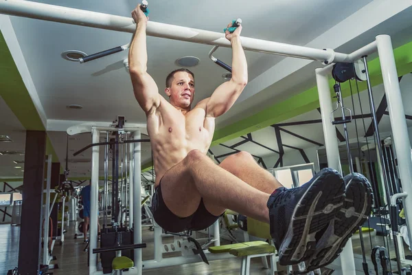 Strong athletic man on pull up bar and legs raised
