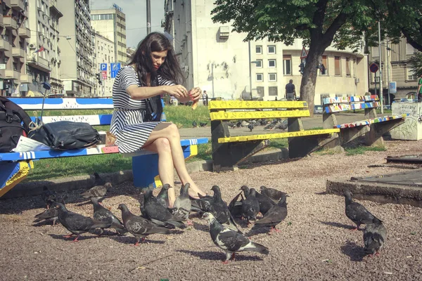 在公园喂鸽子的年轻女子 — 图库照片