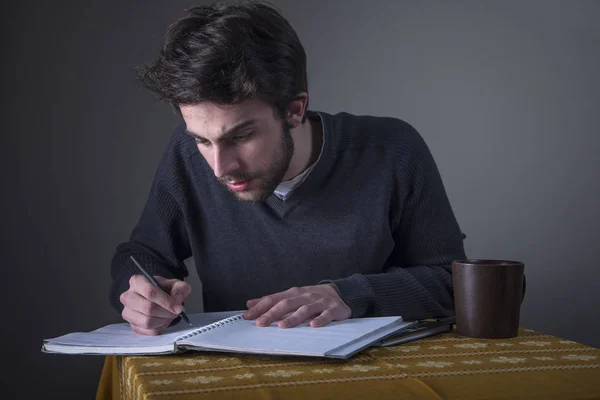 Jeune homme calculant, écrivant et étudiant — Photo