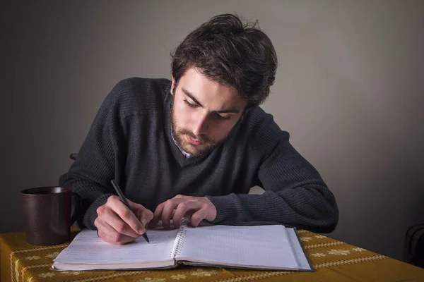 Jeune homme calculant, écrivant et étudiant — Photo