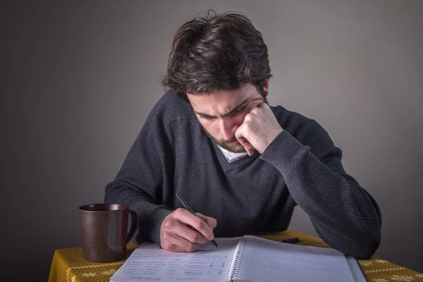 Jeune homme calculant, écrivant et étudiant — Photo