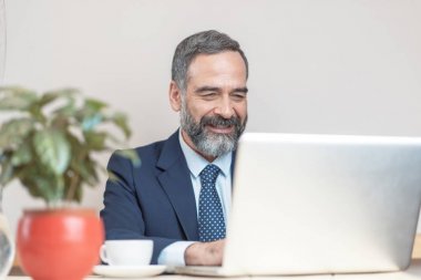 Kıdemli yaşlı iş adamı bir iş molası sırasında bir kafede cep bilgisayarını kullanarak