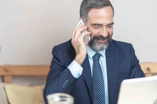 Senior old business man using his cell phone in a coffee shop during a work break