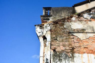 Eski bina, mavi gökyüzü arka planındaki kirli beton duvarı çatlattı.
