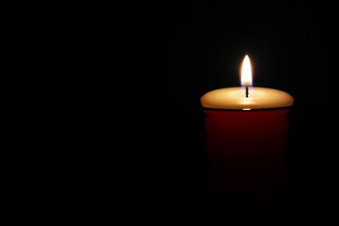 Mum alevi, yanan mum siyah arkaplanda küçük kırmızı bir cam, kopyalama alanı