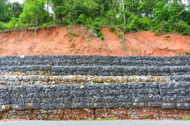 Gabion wall made of stones in the steel mesh, used as a fence on a slope for protection landslide clipart