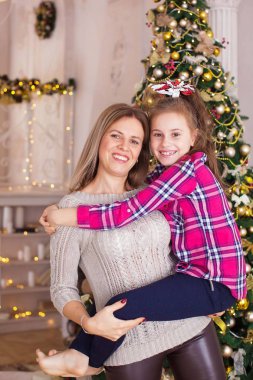 Anne ve kızı, Noel ağacının yanında komik bir kitapla sarılıp gülüyorlar.