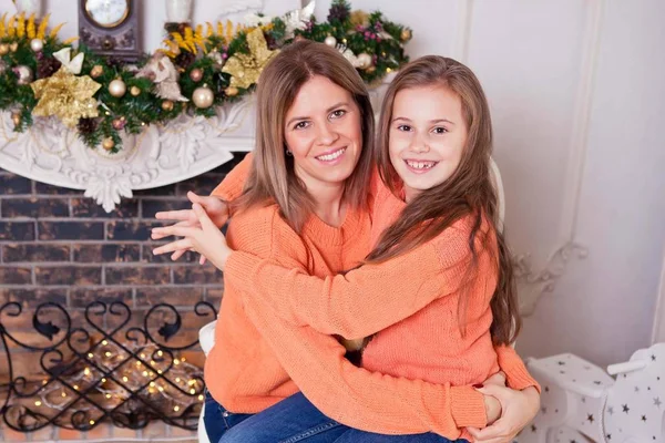 mom and daughter hug and laugh with a book funny near the Christmas tree