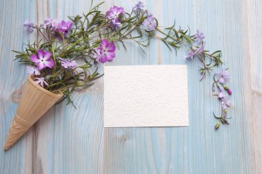 Bahar konsepti Çiçek arkaplan. Mavi ahşap arka planda gül çiçekleri olan dondurma külahı. Metin için boşluk