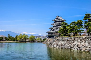 Japonya 'nın arka planında Japon Alpleri olan çarpıcı Matsumoto kalesi.
