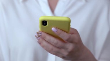 Kadın eli sarı bir çantada telefonu tutar. 