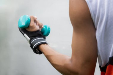 Adam boks antrenmanı sırasında dambılı tutuyor. Güçlüdür.