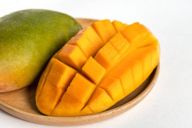 Mango 'nun yakın plan beyaz zemin üzerindeki ahşap tabakta.