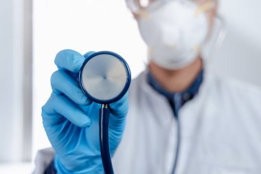 Bir doktor steteskopunu elinde tutarak klinikteki panoramik panoramik ürünleri kontrol etme zamanının geldiğini ima ediyor..