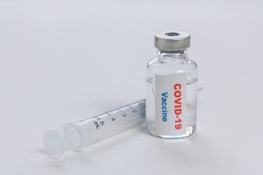 Beyaz zemin üzerinde Covid-19 veya coronavirus aşı şişesi ve şırınga