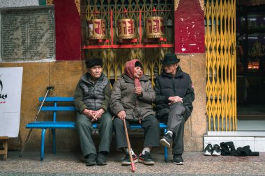 NEW DELHI, INDIA - 9 Aralık 2019: Eski Tibetliler, Delhi 'nin mini tibet olarak da bilinen bir koloni olan Majnu-ka-tilla' daki bir Budist tapınağının dışındaki bankta oturuyorlar.