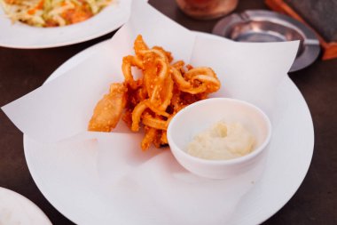 Beyaz tabakta tartar soslu kızarmış kalamar.