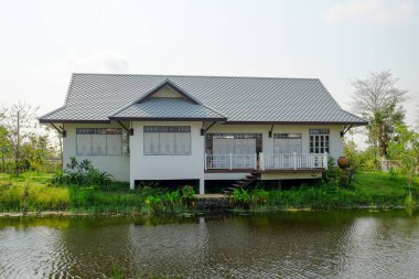 Göletin yanında açık mavi gökyüzü olan bir ev.