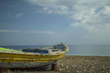 Kumsaldaki sarı tekne. bulutlar arkaplan