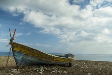 Kumsaldaki sarı tekne. bulutlar arkaplan
