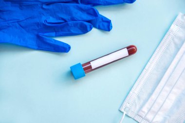 Kan testi konsepti, solunum maskesi mavi arka plandaki doktorun mavi lastik eldivenleri.