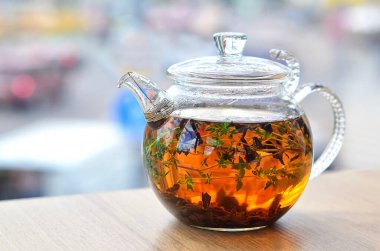 Masanın üzerinde çay ile cam kedi yavrusu var.