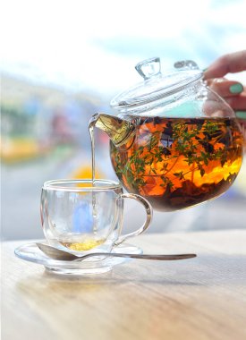 Cam çaydanlıktan cam bir fincana hafif bir arka planda çay dök.