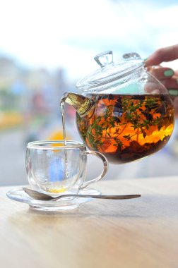 Cam çaydanlıktan cam bir fincana hafif bir arka planda çay dök.