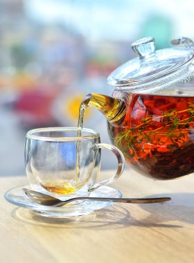 Cam çaydanlıktan cam bir fincana hafif bir arka planda çay dök.