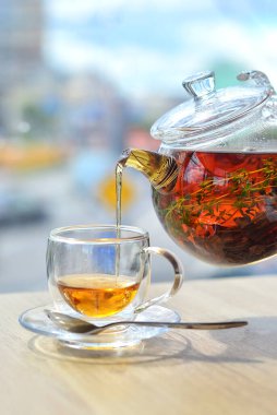 Cam çaydanlıktan cam bir fincana hafif bir arka planda çay dök.